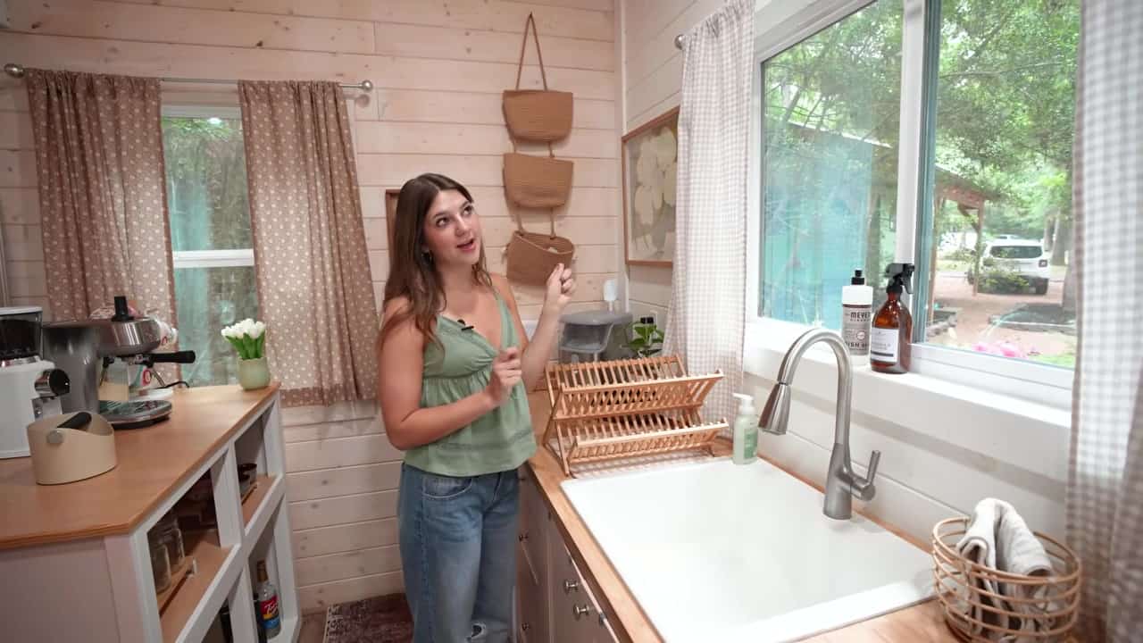 Annie in her DIY tiny house kitchen with wood counters, farmhouse sink, and coffee bar