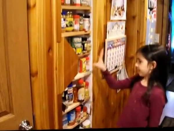 Spice shelves built into the wall between the kitchen and bathroom of the Baird family tiny cabin