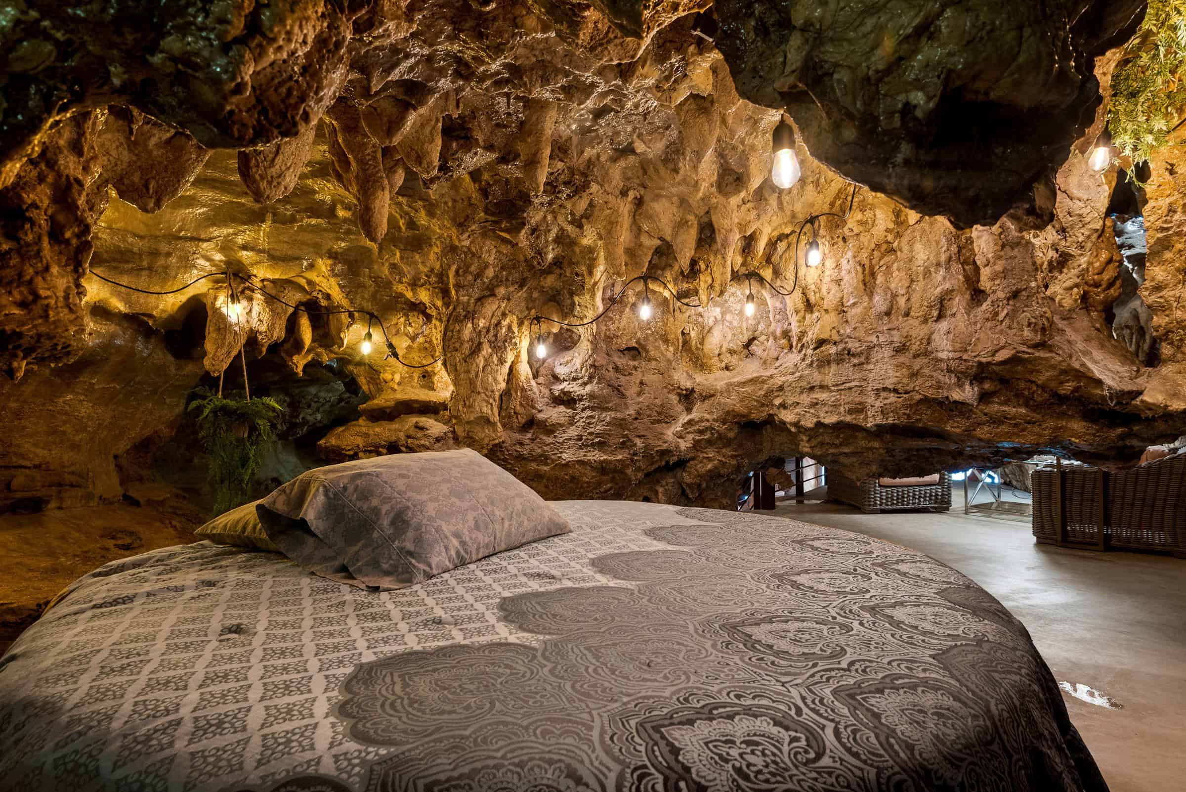 Bed under a cave ceiling with string lights
