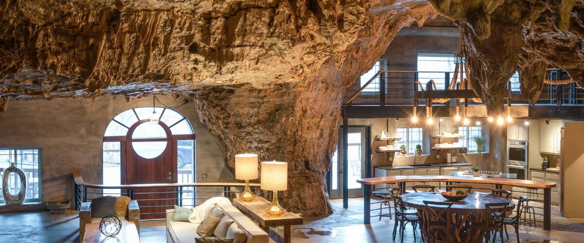 Wide cave interior with living, dining, and a kitchen under the rock ceiling