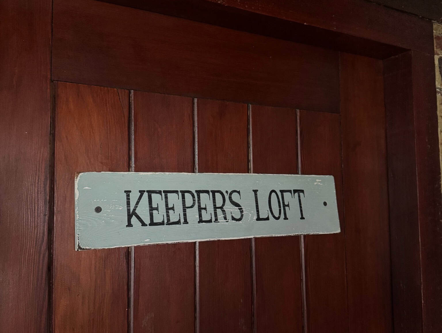 Wooden door with a painted Keeper's Loft sign