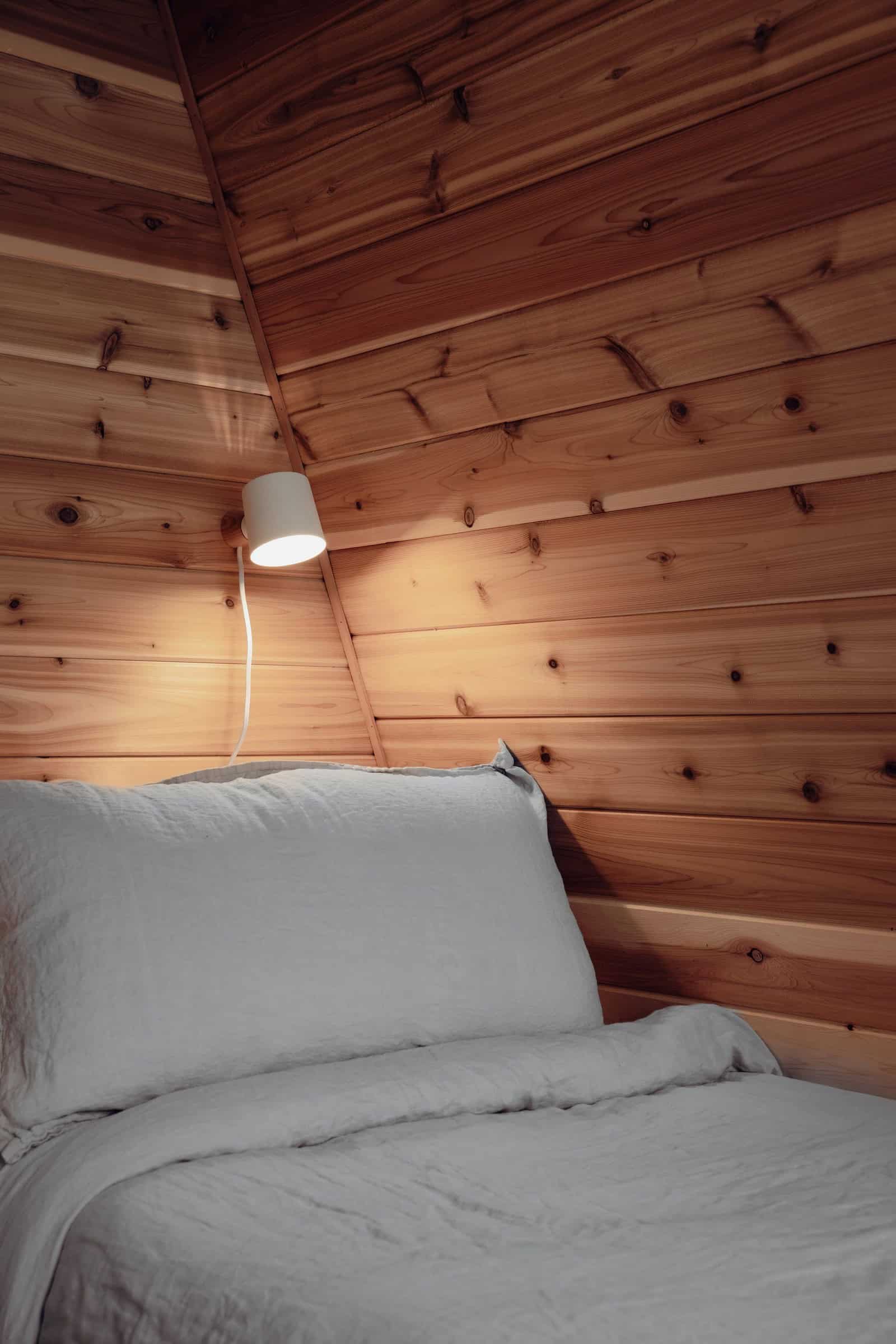 System 00 interior: bunk detail on sloped wood wall with reading lamp