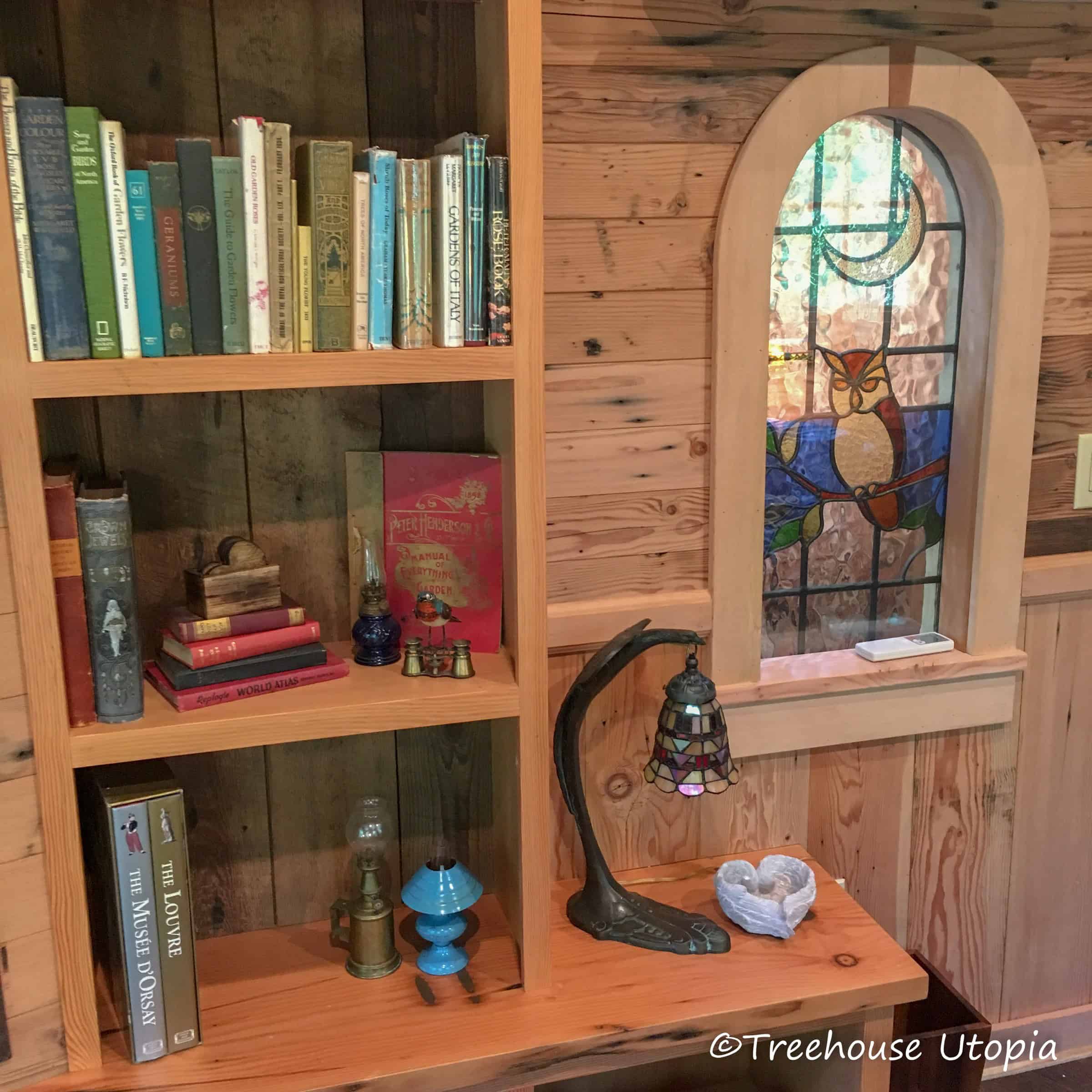 Bookshelves beside an arched owl stained-glass window