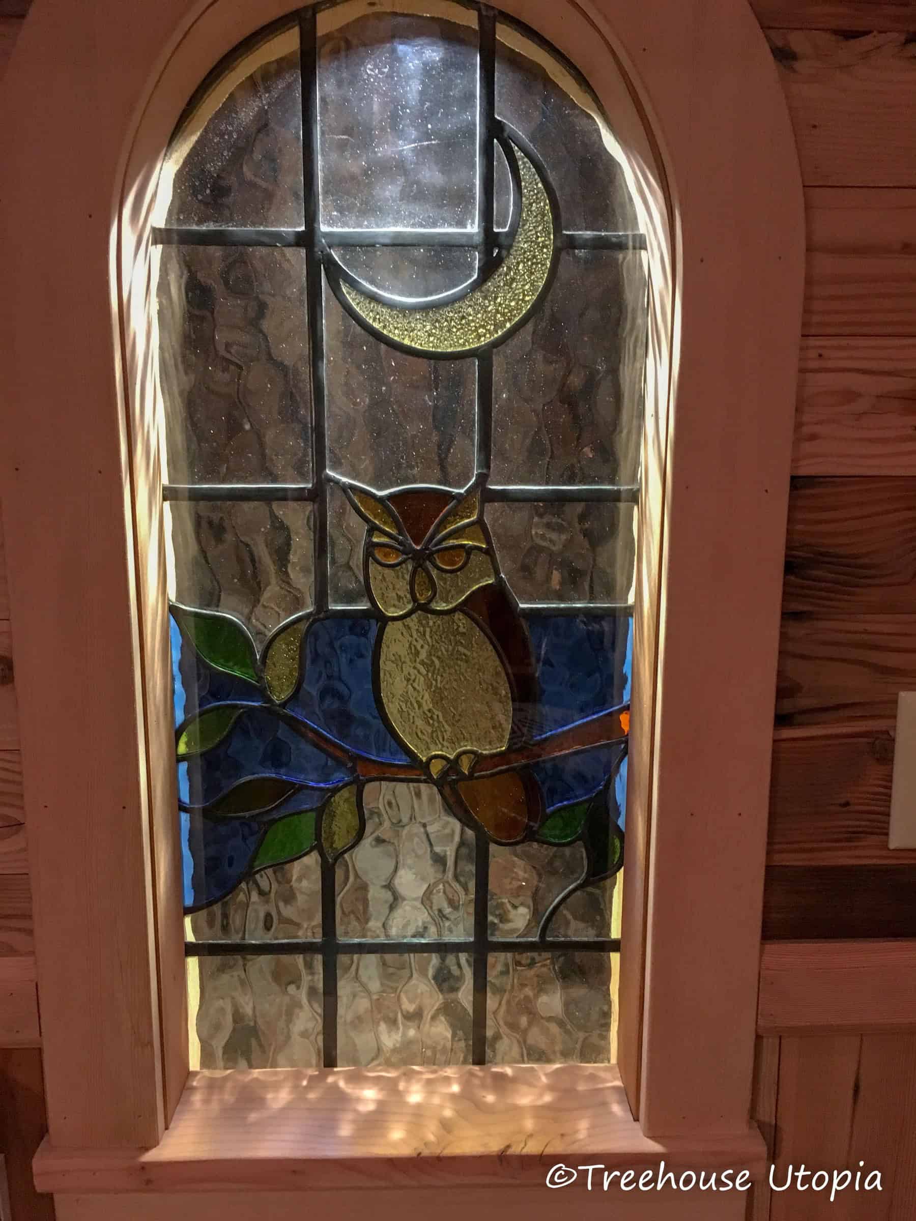 Arched stained-glass window with an owl and a crescent moon