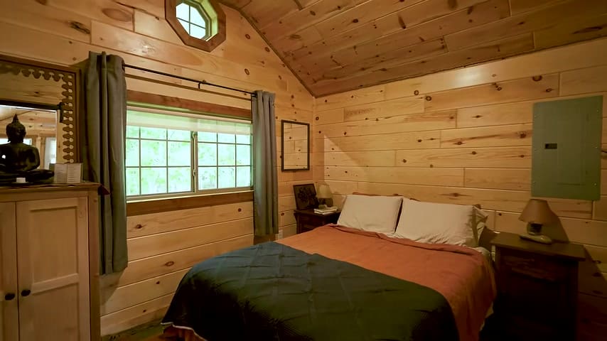 Spacious ground-floor bedroom with vaulted wood ceiling and large window in Brian’s tiny house
