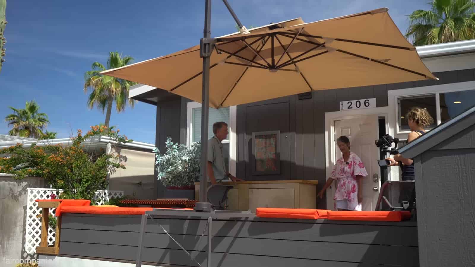 Front deck with shade umbrella, cushioned benches, and storage shed