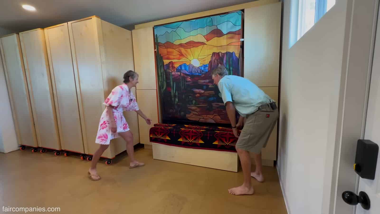 Murphy bed folded behind a painting with its base used as a bench