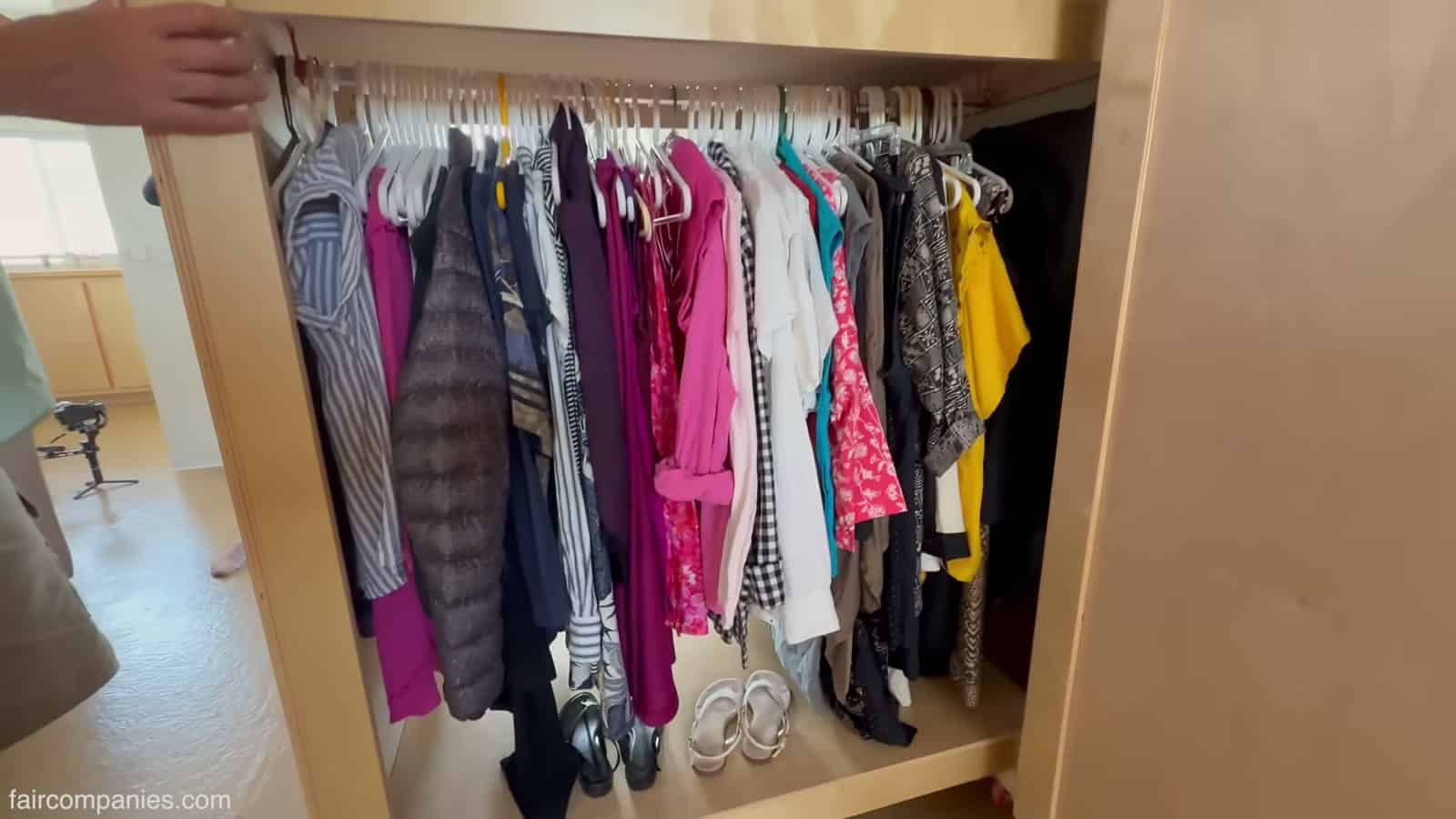 Rolling wardrobe cabinet pulled out to reveal hanging clothes