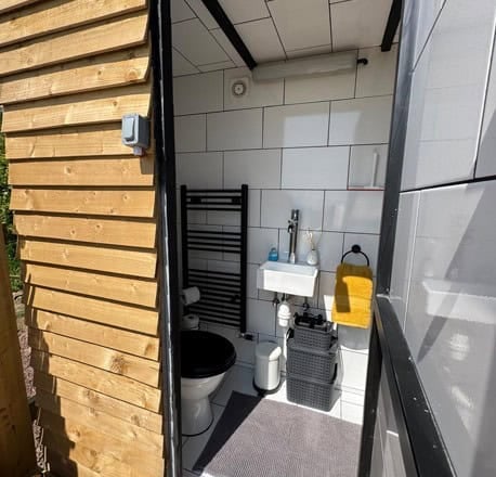 Tiled bathroom with a towel radiator, small sink, and toilet