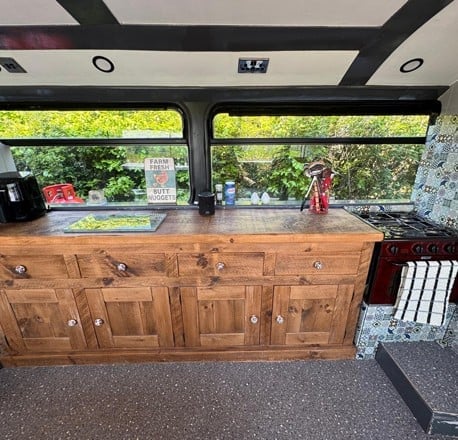 Wood kitchen cabinets under the bus windows with green hills outside
