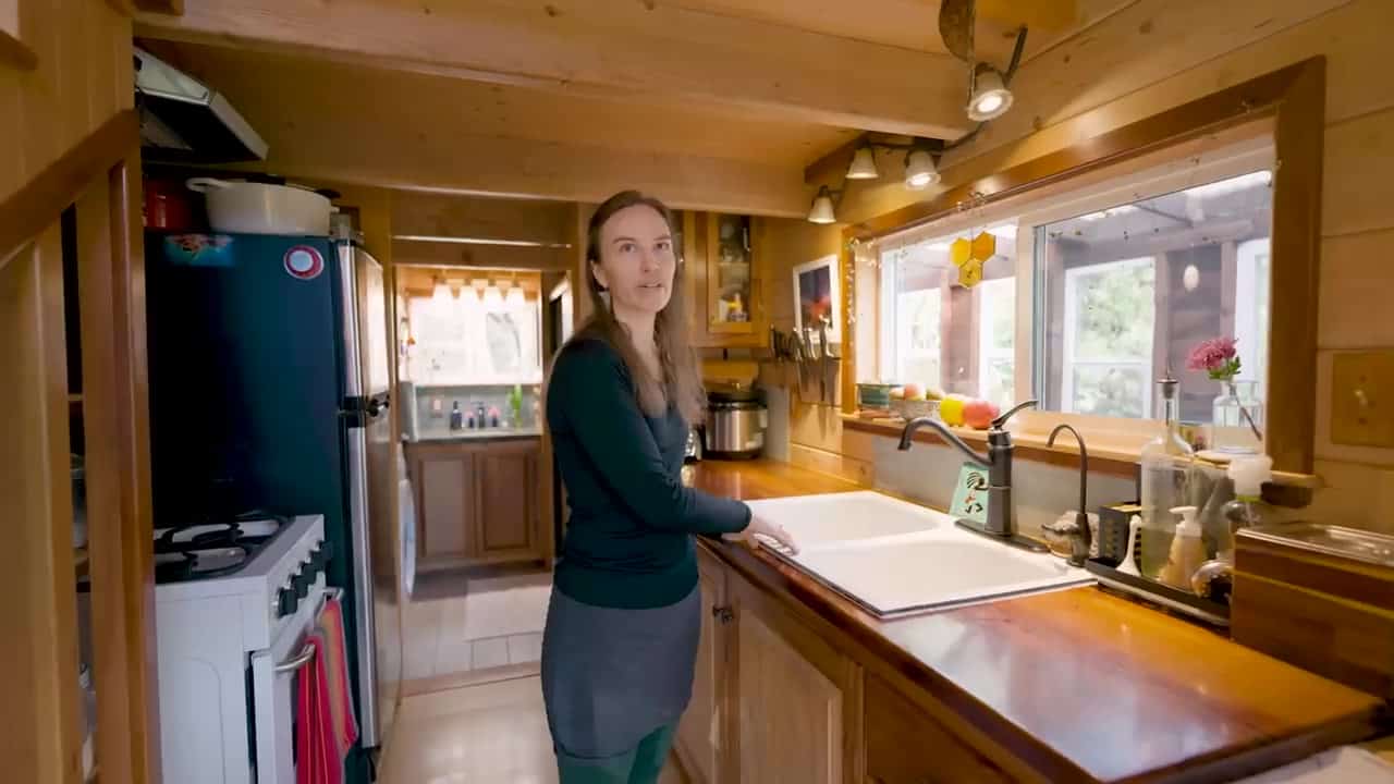 Galley kitchen with a large white cast-iron sink, live-edge wood counter, compact gas range, and stainless fridge