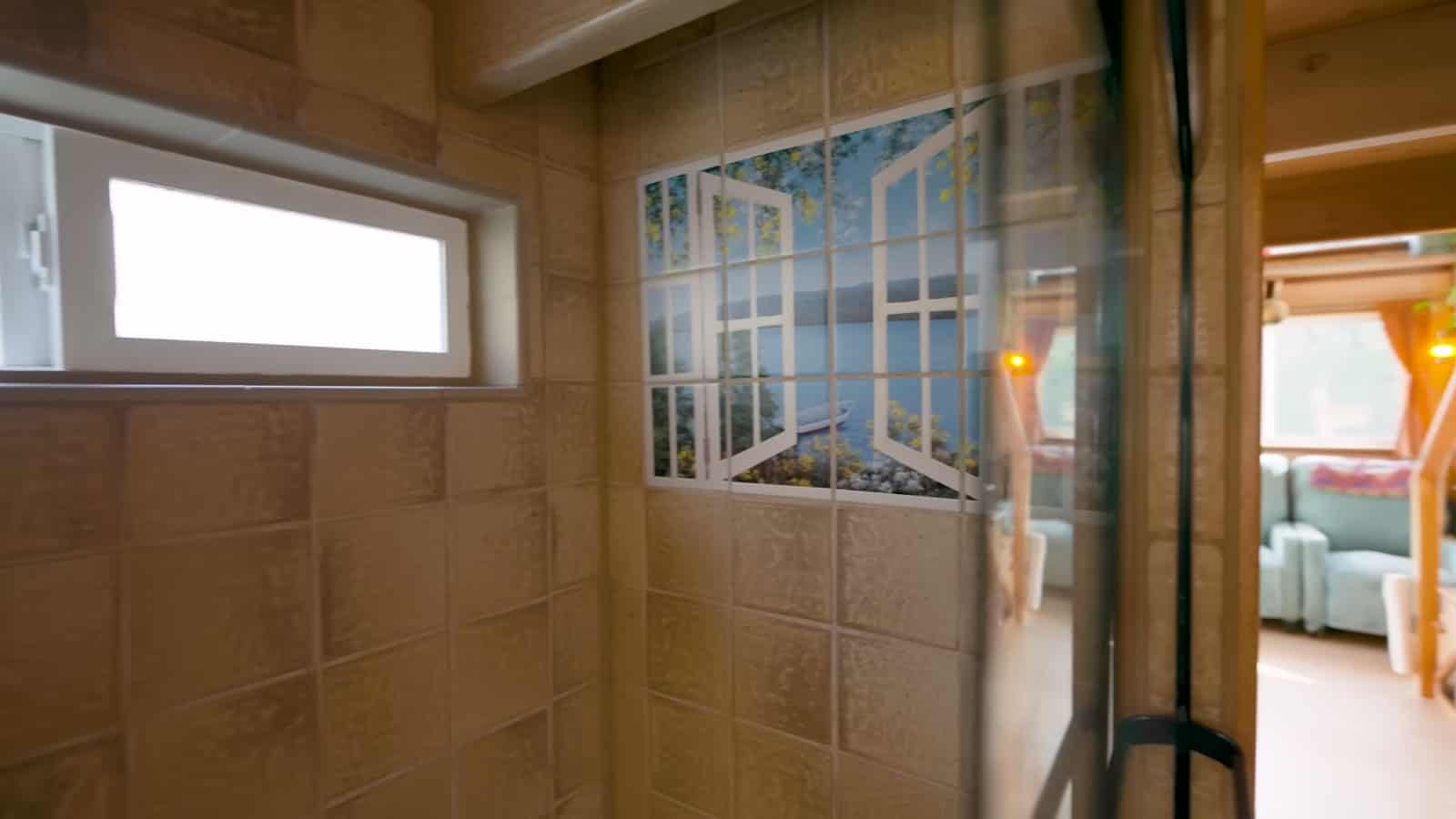 Inside a full-size tiled shower with a clerestory window and a glass-block style divider