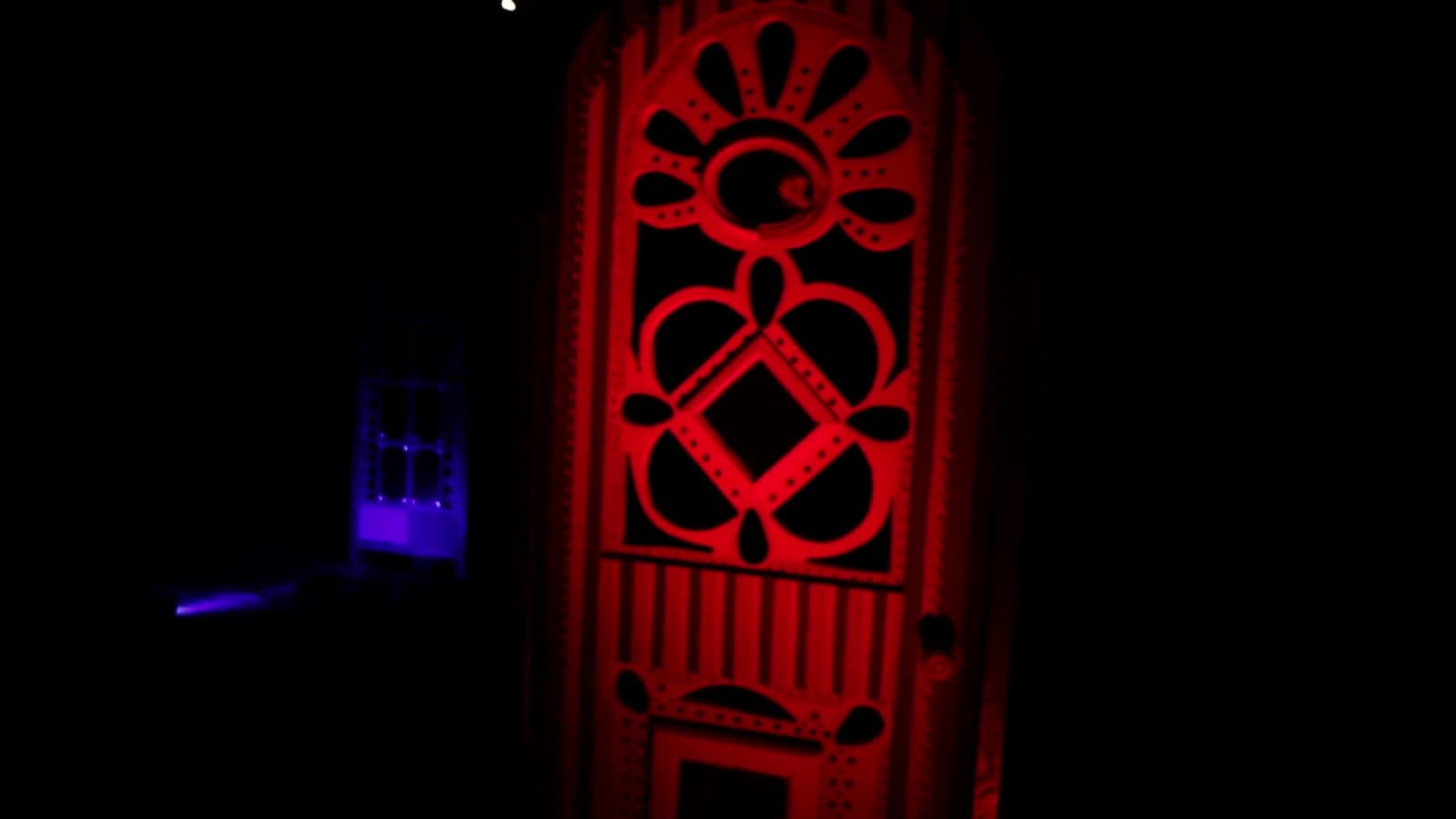 A glowing red art door from The Unknown Zone installation at night