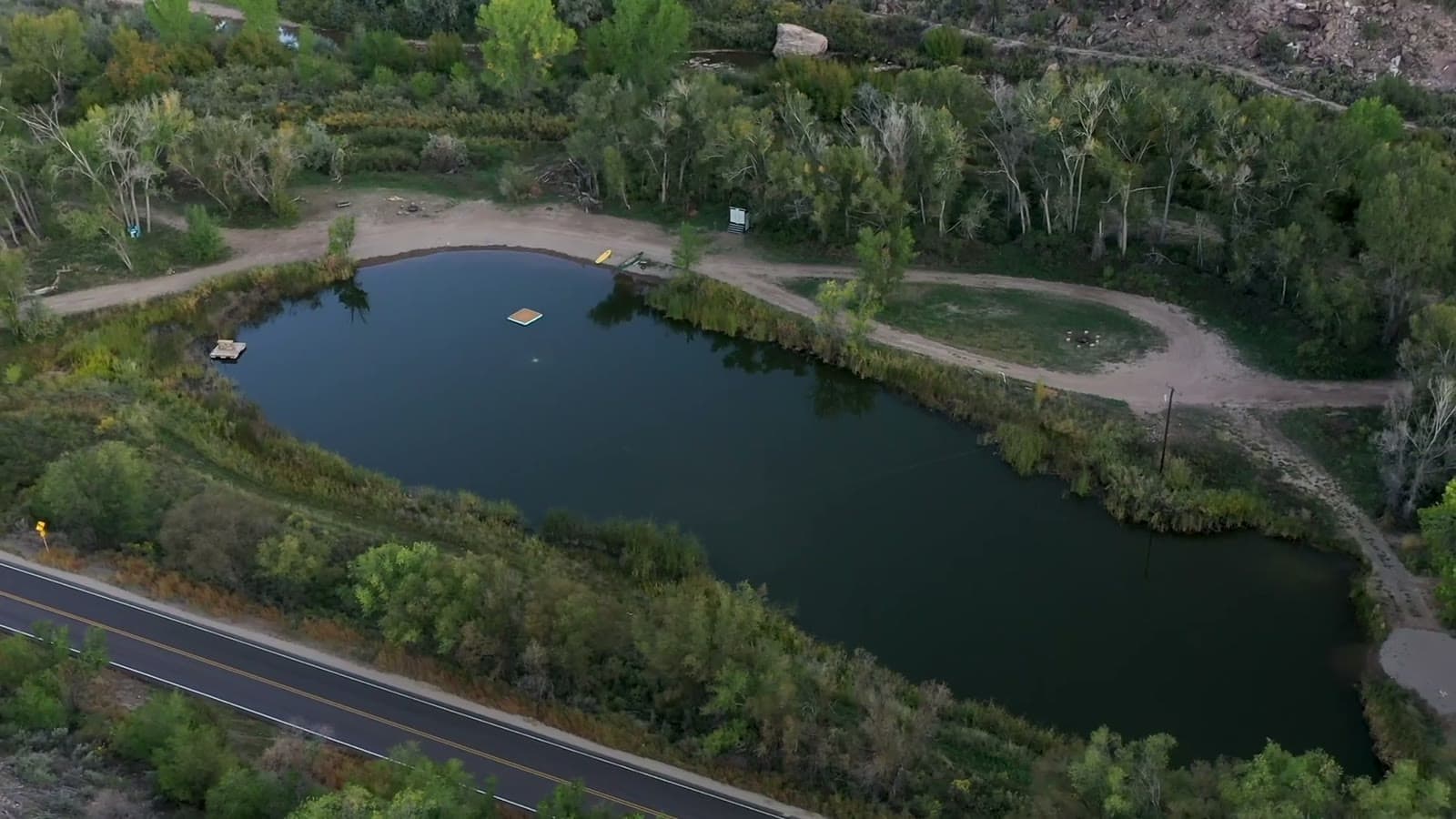 Aerial view of Lake V pond surrounded by trees and trails at Camp V