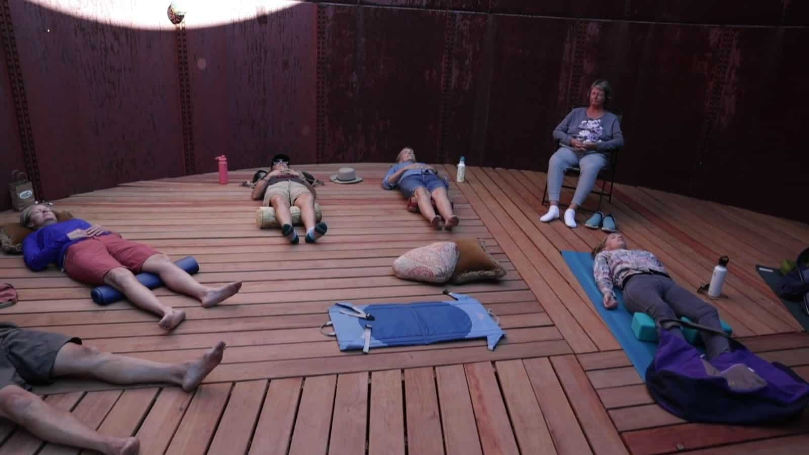 Guests relaxing on mats during a sound bath inside the water tank studio