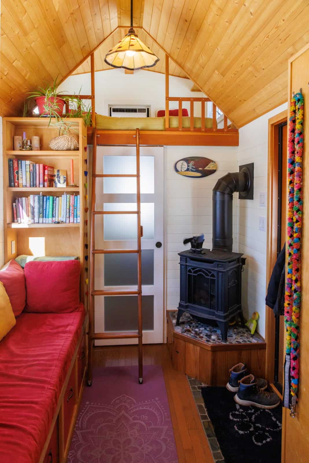 View toward the propane stove and guest loft ladder with tall bookshelves in the tiny house