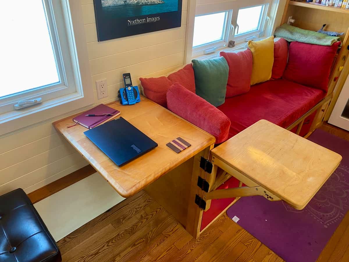 Fold-down wooden desk with laptop next to the built-in couch