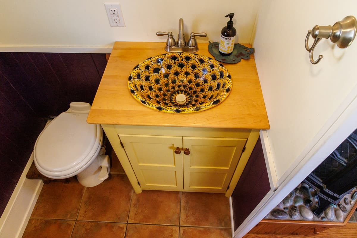 Hand-painted sink in a wooden vanity beside a Dometic toilet