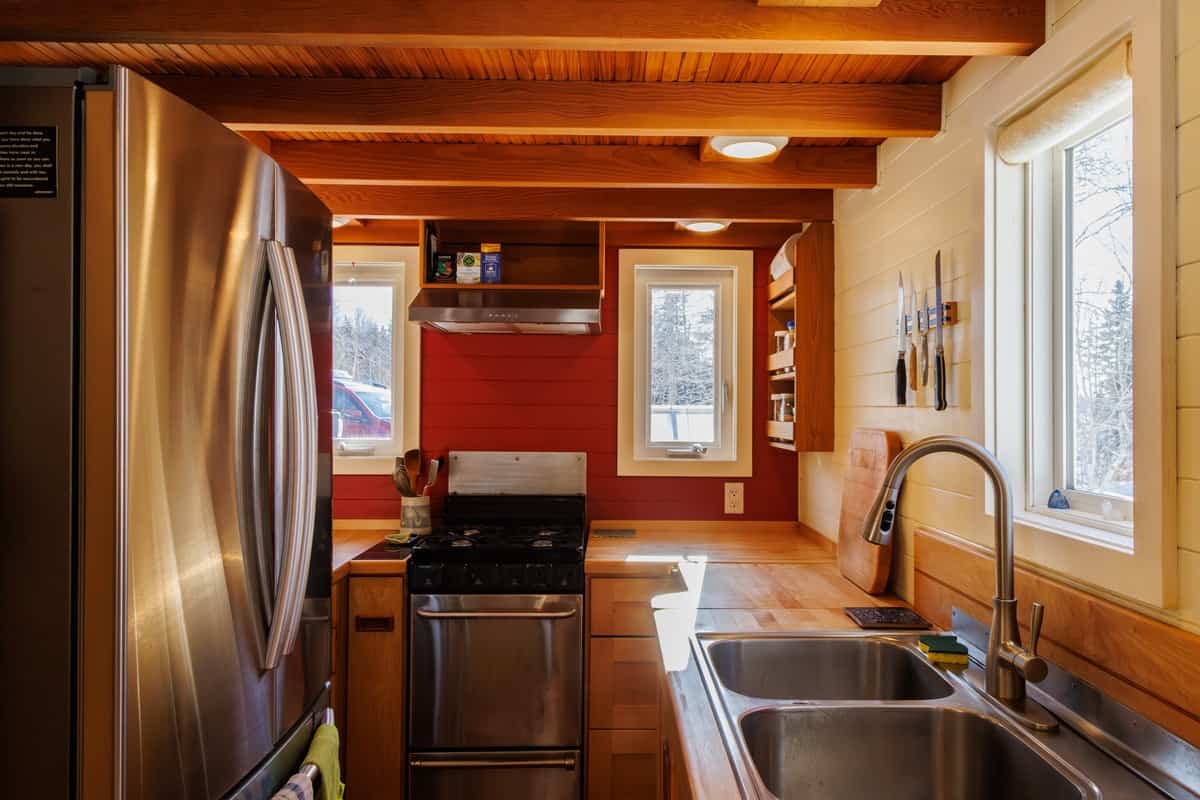 Tiny house kitchen with French door fridge, propane stove and double stainless sink