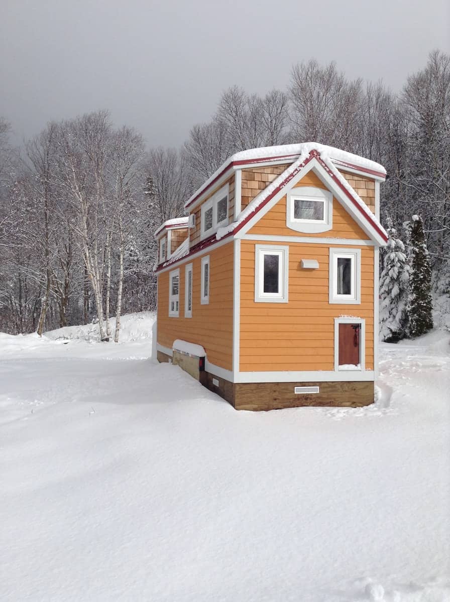 The orange tiny house with red roof surrounded by snow in winter