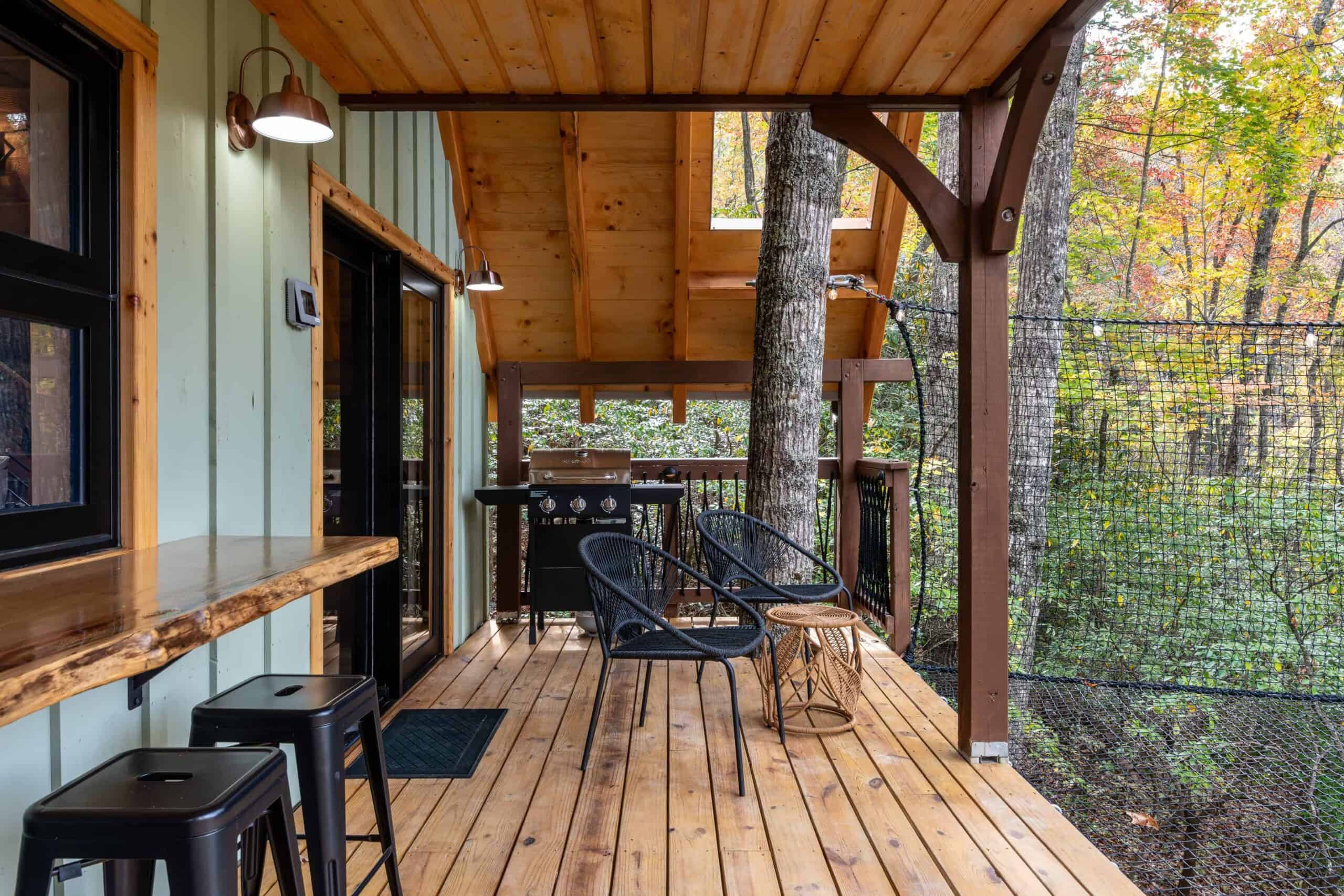 Covered deck at The Carpentree with live-edge bar, grill, and the edge of the sky net