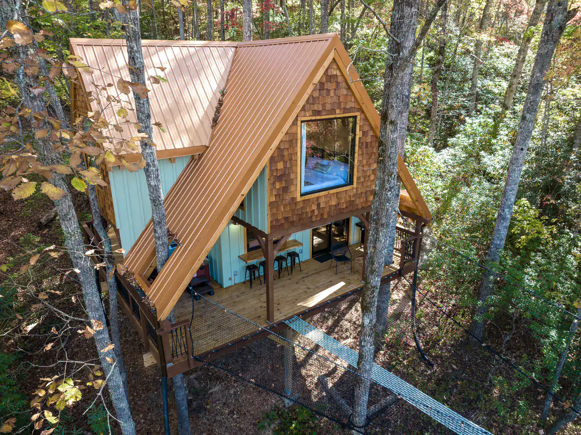 Elevated exterior of The Carpentree showing decks and suspended net among four trees