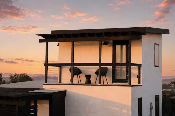 Upstairs balcony of Casita Conejo with two chairs and a small table at dusk