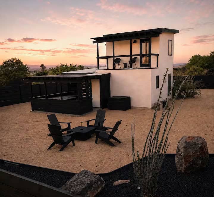 Casita Conejo from the desert yard, with Adirondack chairs around a fire pit and the upstairs balcony