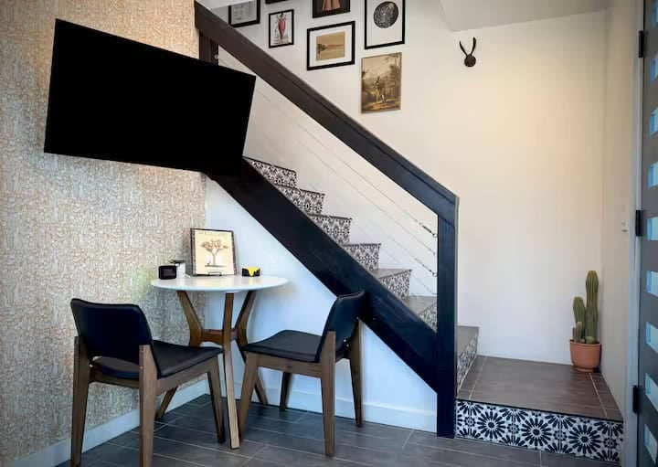 Bistro table for two beside the staircase, with framed art and a rabbit wall mount