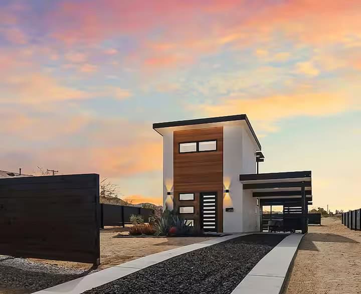 Casita Conejo two-story tiny home in Joshua Tree at sunset with a gravel path to the front door