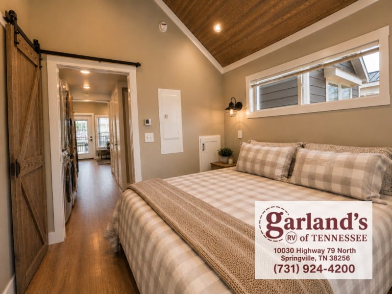Main-floor bedroom with plaid bedding, wood ceiling, and a sliding barn door