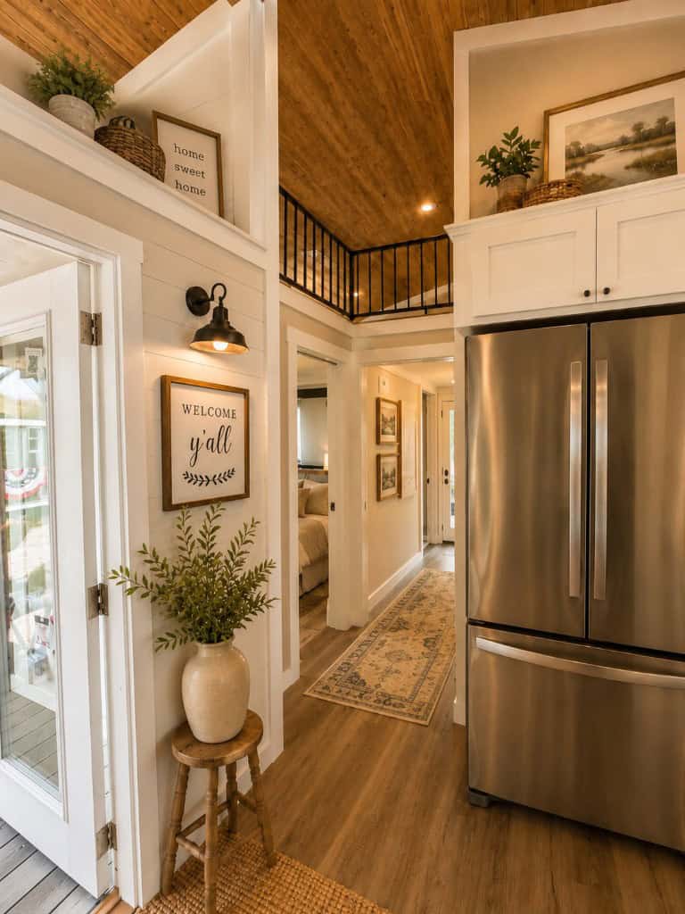 Wheeler interior hall: white shiplap, wood-plank ceiling, stainless fridge, loft rail, WELCOME y'all sign — not the sunset JPEG