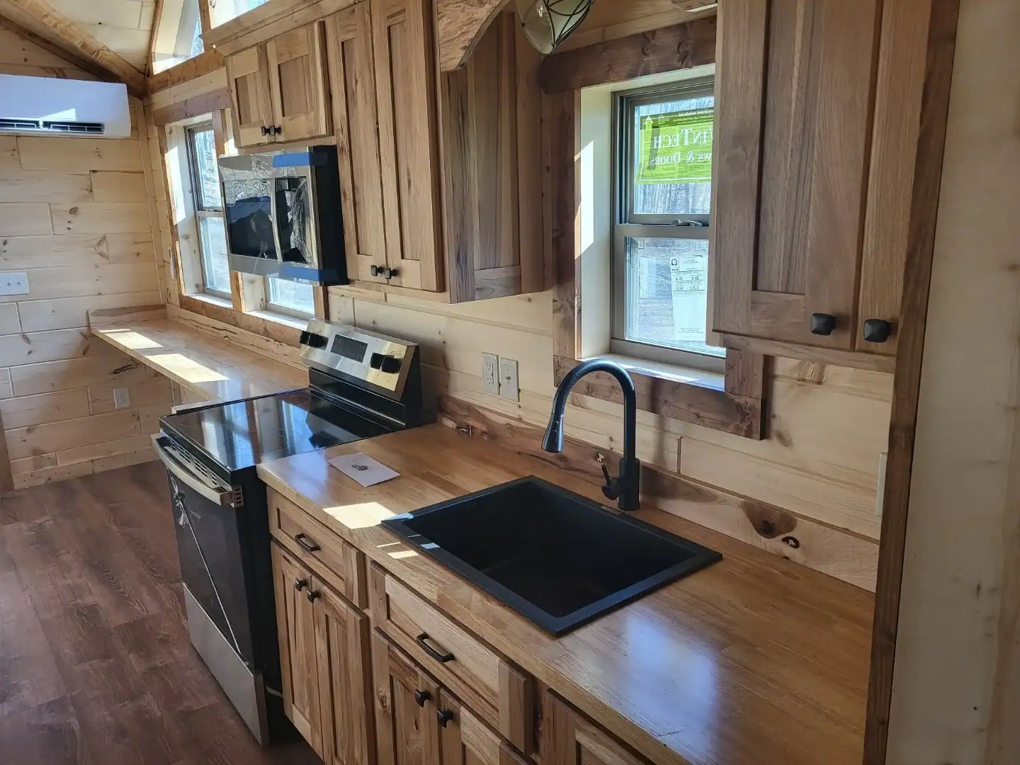Cherokee cottage kitchen with rustic wood cabinets, butcher-block counters, a black farmhouse sink, stainless range, and a mini-split above