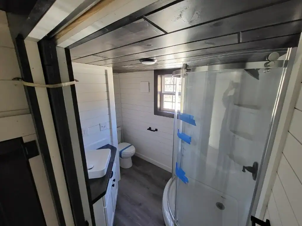 Woodland cottage bathroom with a glass corner shower, toilet, and white shiplap walls