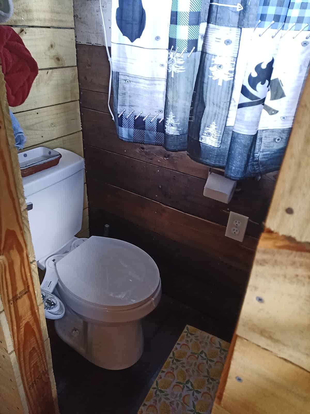 White conventional toilet in a compact bathroom with horizontal wood-plank walls