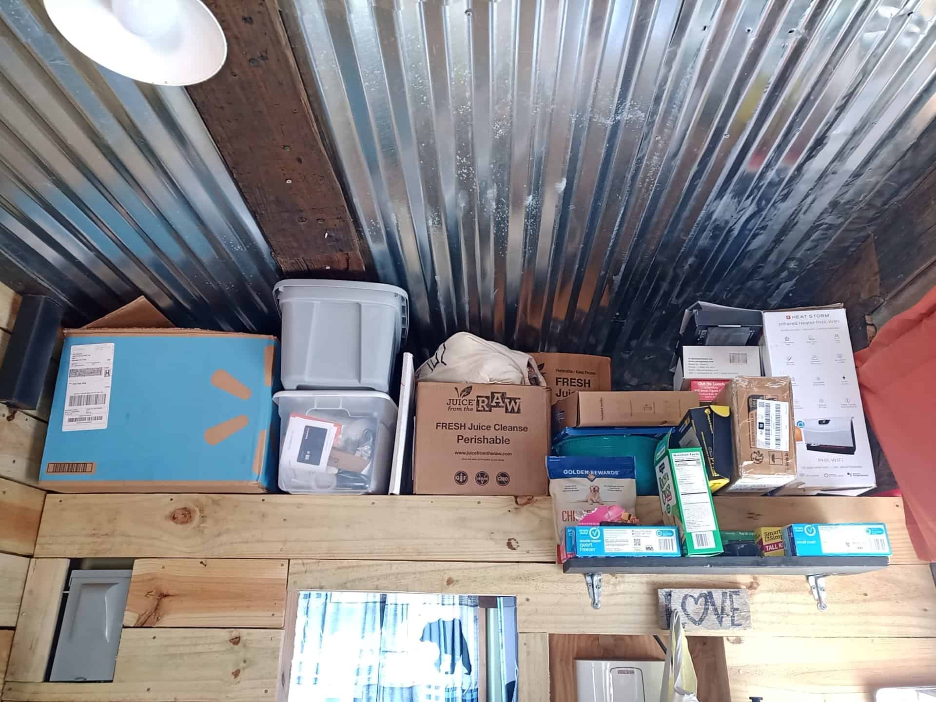 Storage loft of light wood planks under a corrugated-metal ceiling, stacked with bins and boxes