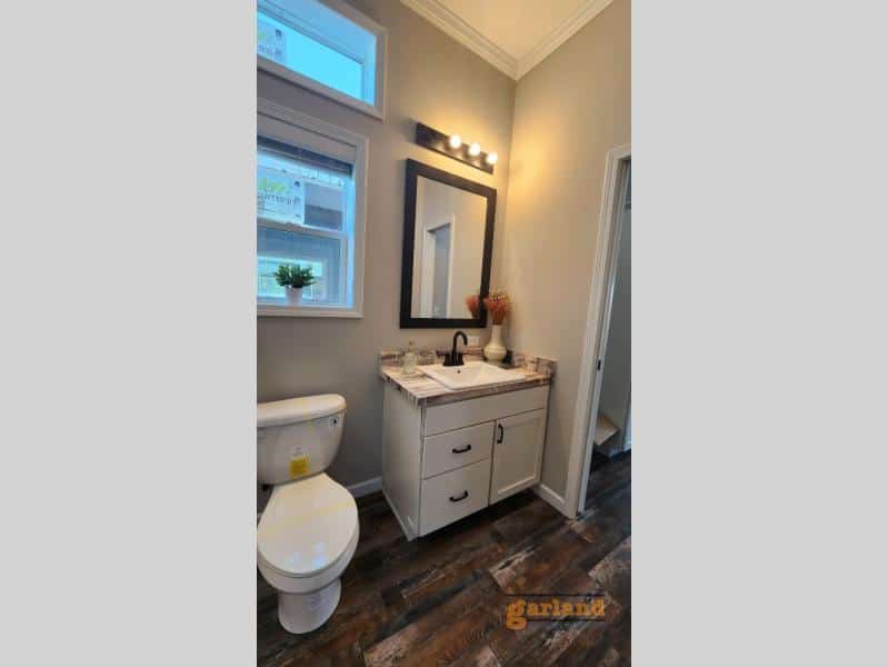 Cozy Cabin bath vanity with wood-look top, black faucet, three-bulb wood bar light