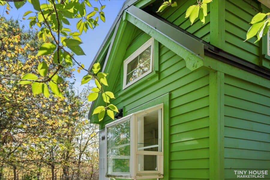 Architect-designed tiny house on wheels featuring vibrant green siding and large windows.