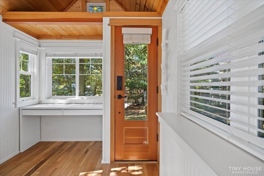 Cozy tiny house interior with large windows and wooden accents for small space living.