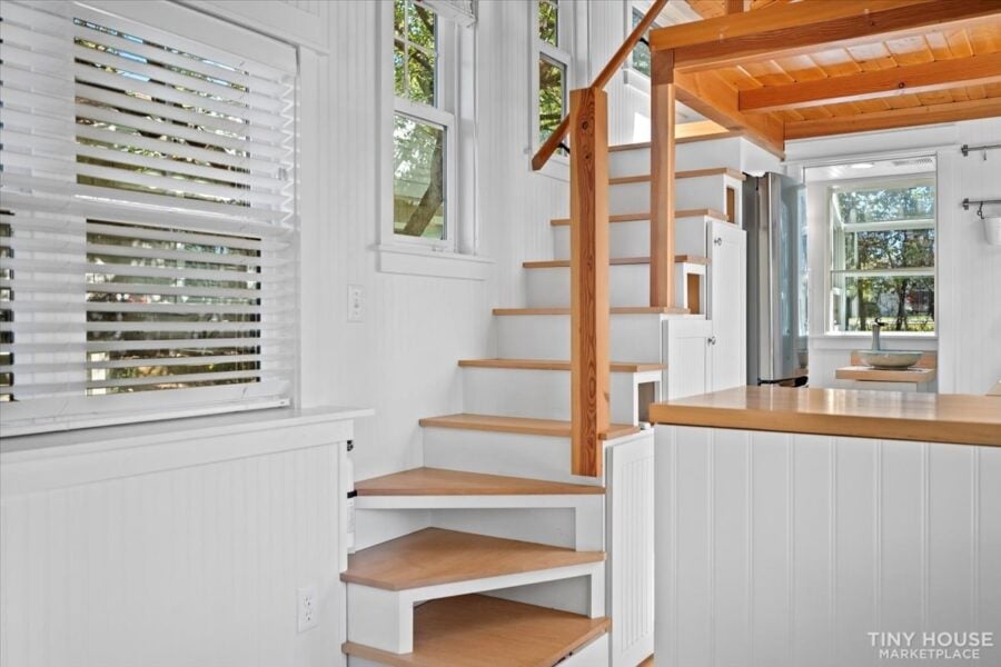 Modern tiny house interior with wooden stairs and bright natural light.