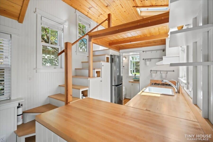 Modern tiny house interior with compact kitchen and loft space on wheels.