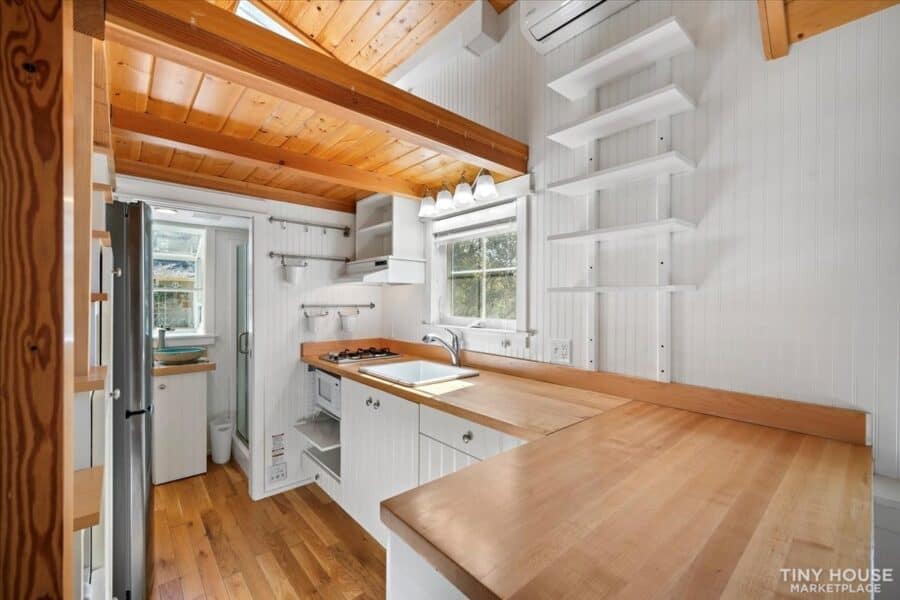 Tiny House on Wheels - Compact kitchen with white cabinetry and wooden accents.