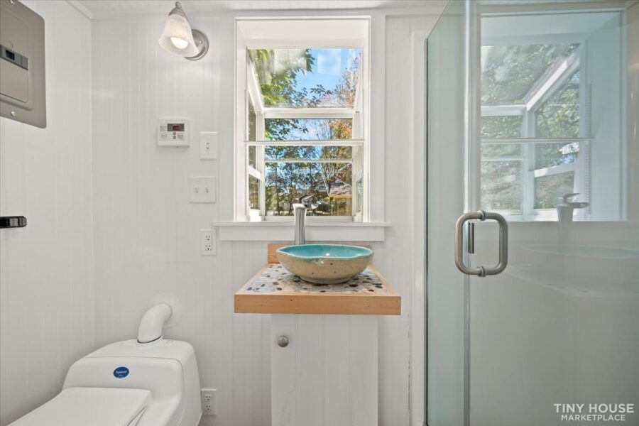 Compact tiny house bathroom featuring a shower, window, and modern fixtures.