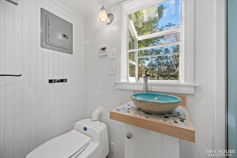 Bathroom in a tiny house with a large window, white walls, and minimalist design.