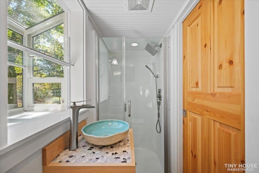 Bathroom in architect-designed tiny house on wheels with natural wood accents and a modern shower.