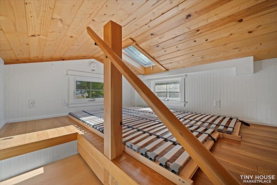 Cozy tiny house interior with wooden ceiling and skylight for small space living.