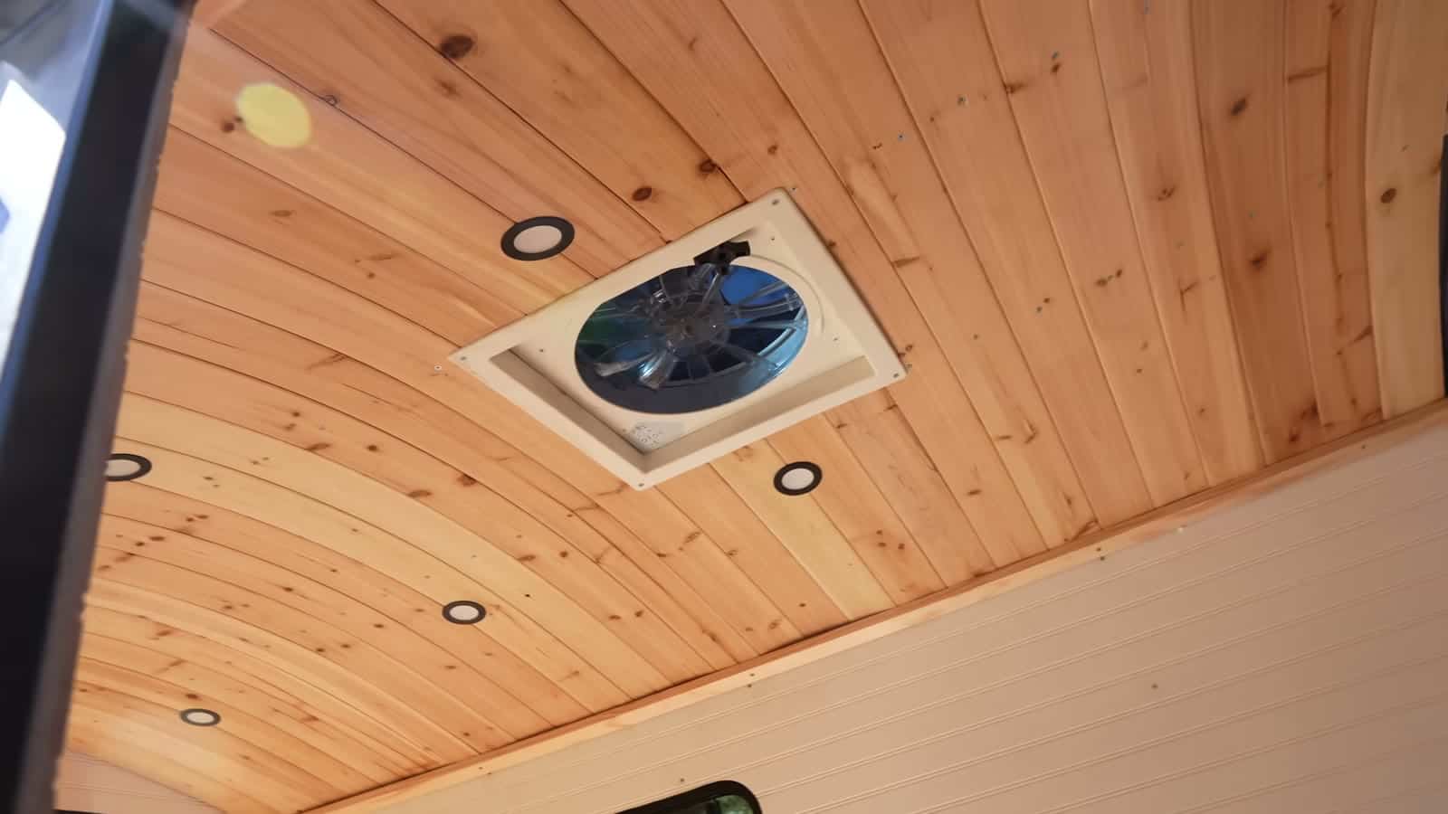 Arched tongue-and-groove cedar ceiling with recessed lights and roof vent fan
