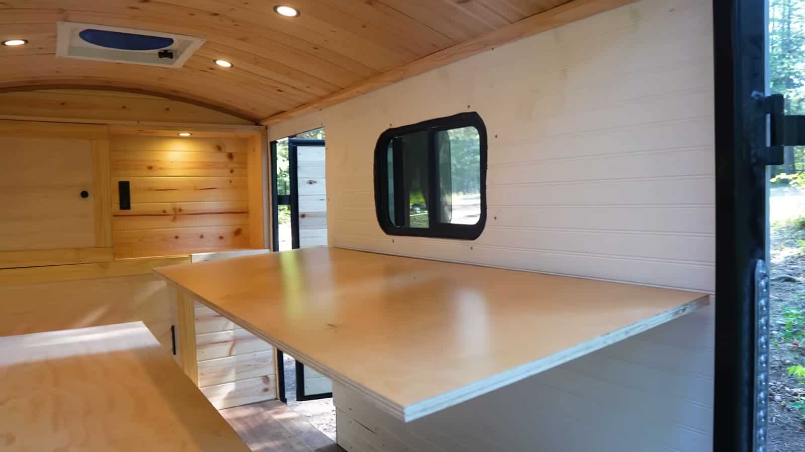 Oak plywood desk on E-track brackets next to the bed inside the cargo trailer camper