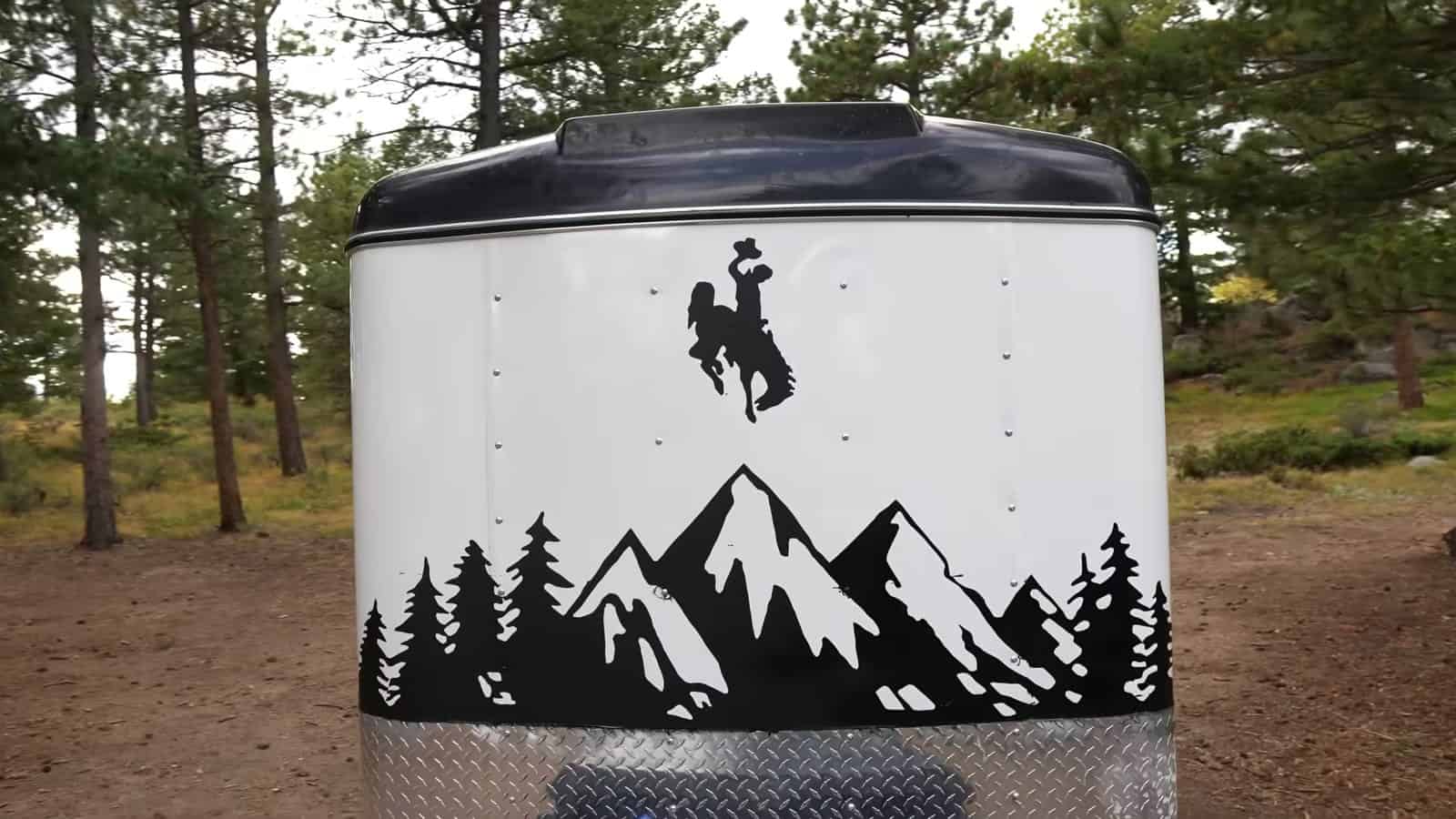 Front of the trailer painted with mountains, pines, and a bucking horse silhouette