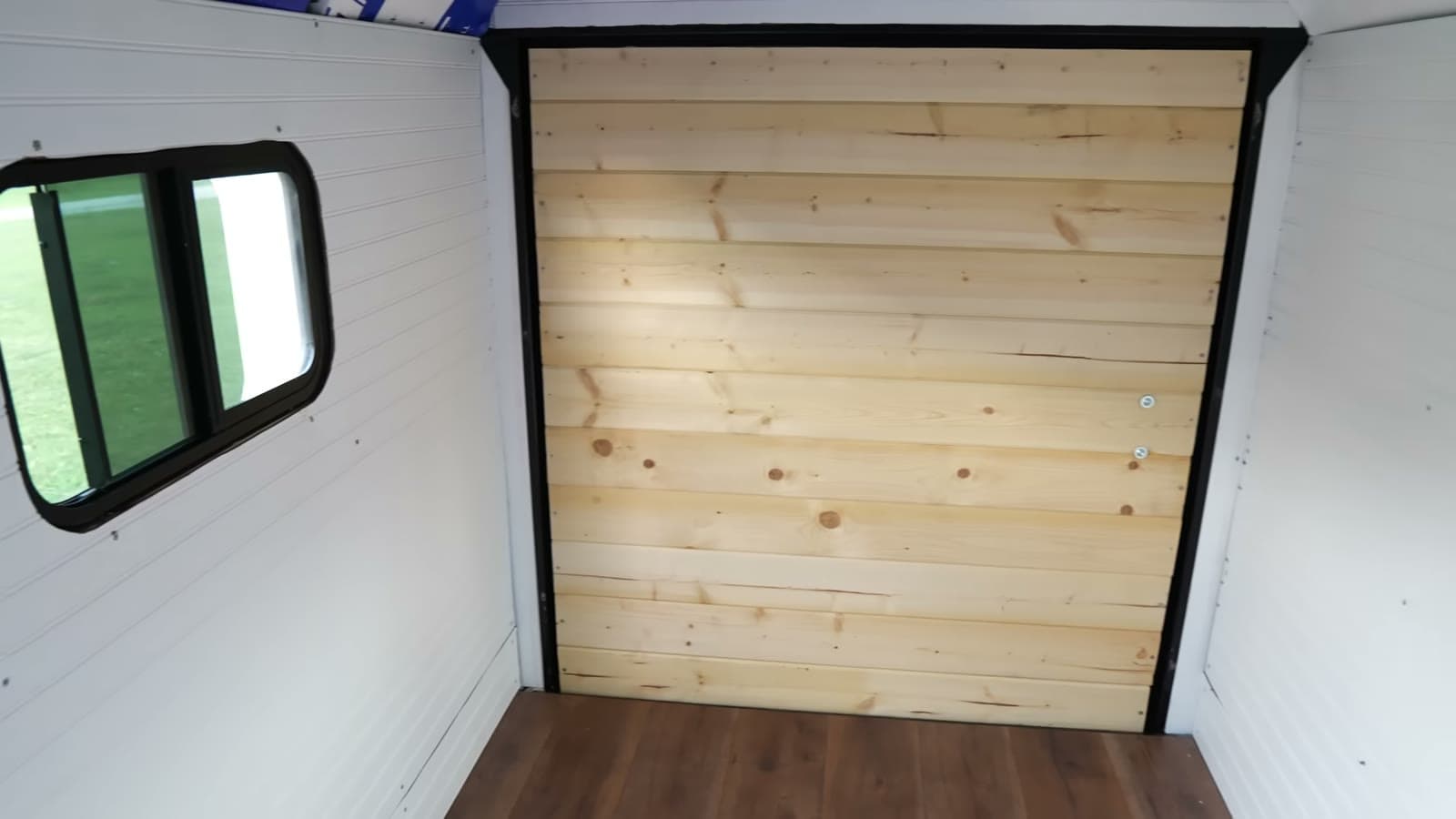White paneled walls, RV window, and tongue-and-groove cedar on the rear doors